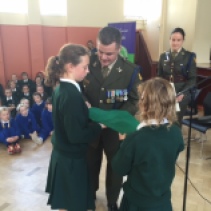 Sergeant Wayne Eastwood presenting the National Flag to Aisling and Blátnid